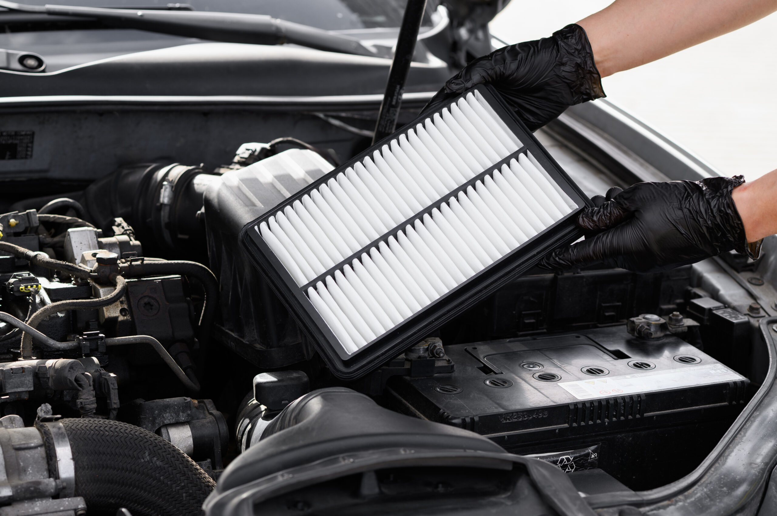 Car Mechanic Holds Car Air Filter In Hands Near Engine Compartment, Plans To Replace Old Filter, Close Up. Concept Replacing Auto Parts, Car Maintenance, Protection From Allergens, Dirt, Soot